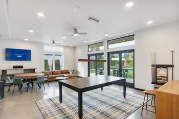 A modern living room with a black table and a flat screen TV mounted on the wall.